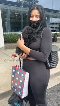 a woman wearing a mask holding a poodle